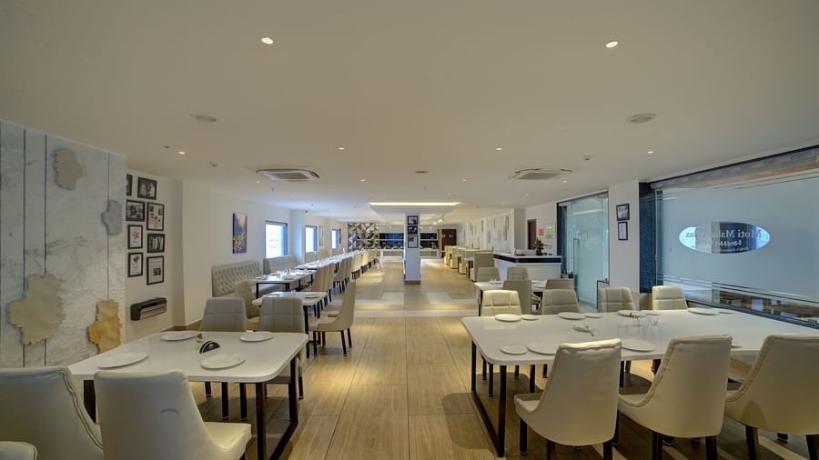 A pathway in the middle of the restaurant with dining tables and chairs in both sides of it at Ilara Hotels & Spa, Tada.