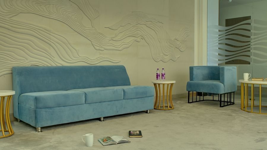 A plush blue couch in the lounge area with a few books kept on the floor at Ilara Hotels & Spa, Tada.