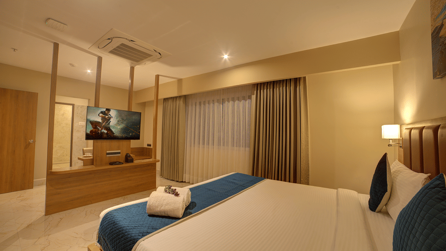 A wide-angle shot of the bedroom at Ilara Hotels & Spa, Tada at the Executive Suite with a plush double bed and a flat screen television in front of it.