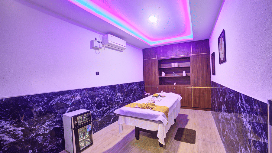 Corner-view shot of a room with ambient lighting from the false ceiling featuring a spa bed in the middle at Ilara Hotels & Spa, Tada.