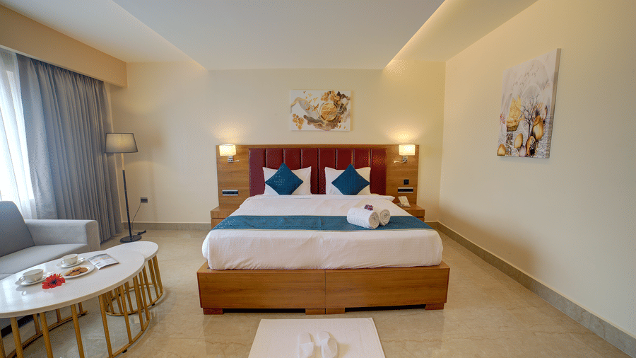 Front-view shot of a comfortable double bed in the junior Suite with a common seating area besides it at Ilara Hotels & Spa, Tada.
