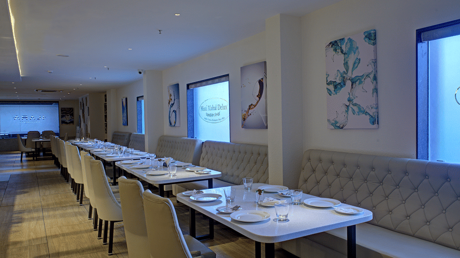 Corner-view shot of the Moti Mahal Restaurant with dim lighting falling on the dining tables from the translucent glass windows at Ilara Hotels & Spa, Tada.