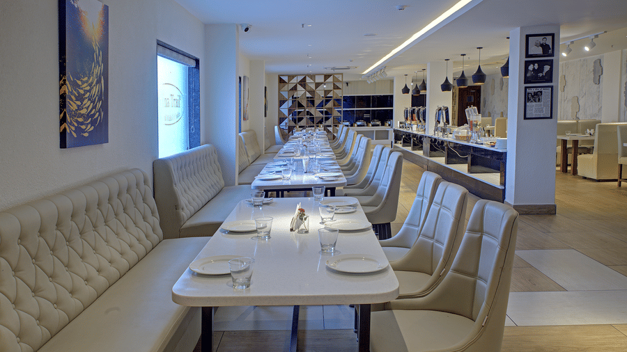 Side-angle view of the dining tables with plates kept on it at Moti Mahal restaurant at Ilara Hotels & Spa, Tada.