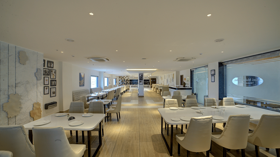 A pathway in the middle of the restaurant with dining tables and chairs in both sides of it at Ilara Hotels & Spa, Tada.