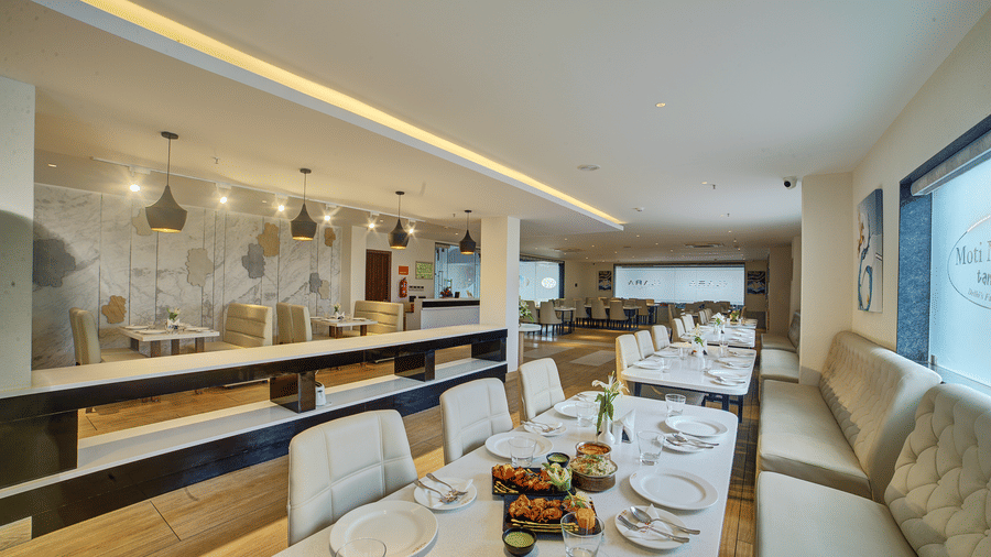 The interiors of a brightly lit dining area with beautifully served dishes on the table at Ilara Hotels & Spa, Tada.