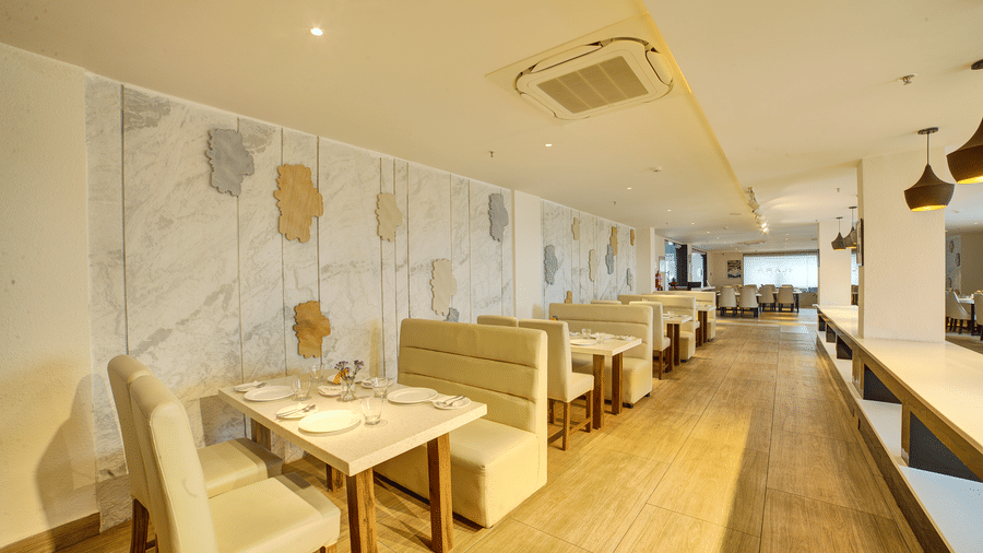A wide-angle shot of the dining area at Ilara Hotels & Spa, Tada with cushioned couches around the dining tables at Moti Mahal.
