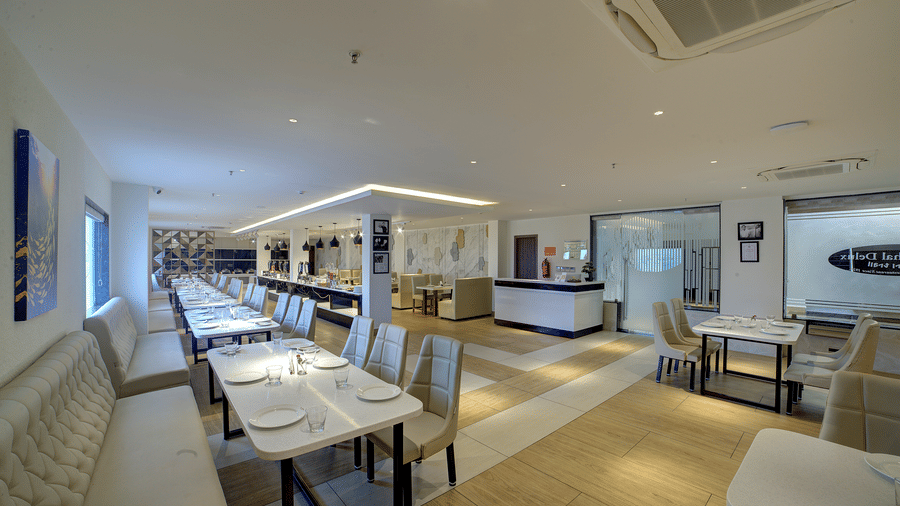 A wide-angle shot of the Moti Mahal Restaurant T Ilara Hotels & Spa, Tada with white porcelain plates kept on the dining tables.