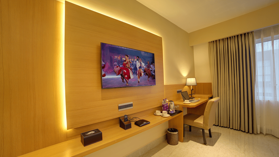 Corner-view shot of the TV table with a wall-mounted flat-screen television and a work station in the corner of the Signature Suite at Ilara Hotels & Spa, Tada.