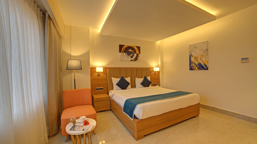 Corner-view shot of the Signature Suite featuring a double bed with a cyan bed runner over it at Ilara Hotels & Spa, Tada.