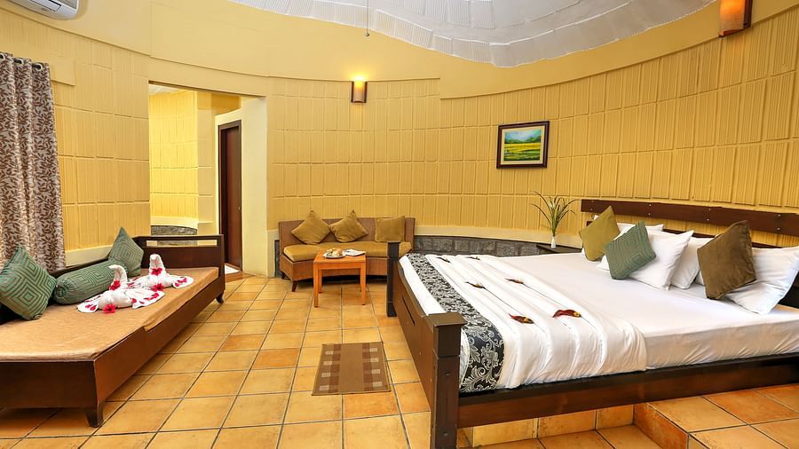 a bedroom with a large bed opposite a sofa cum bed and another sofa on the side - Kadkani River Resort, Coorg