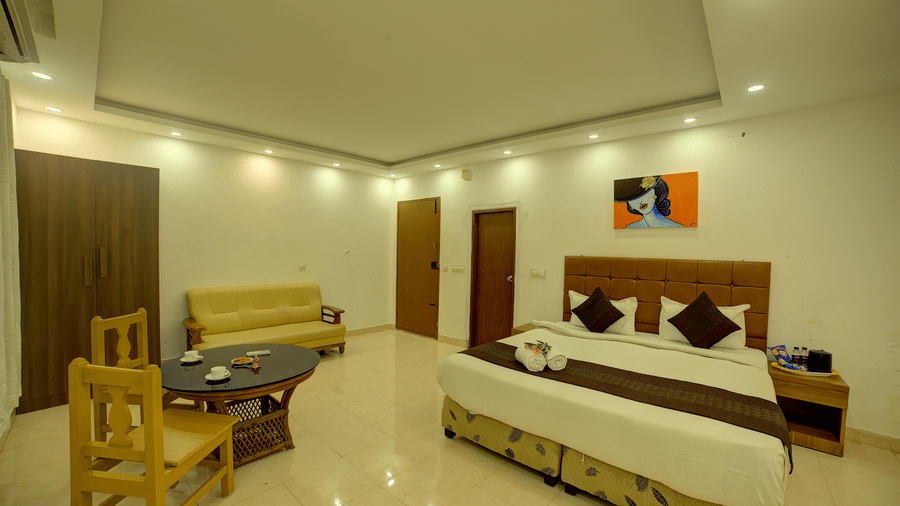 Spacious bedroom with soft lighting and a small dining setup at Kailash Conventions ECR.