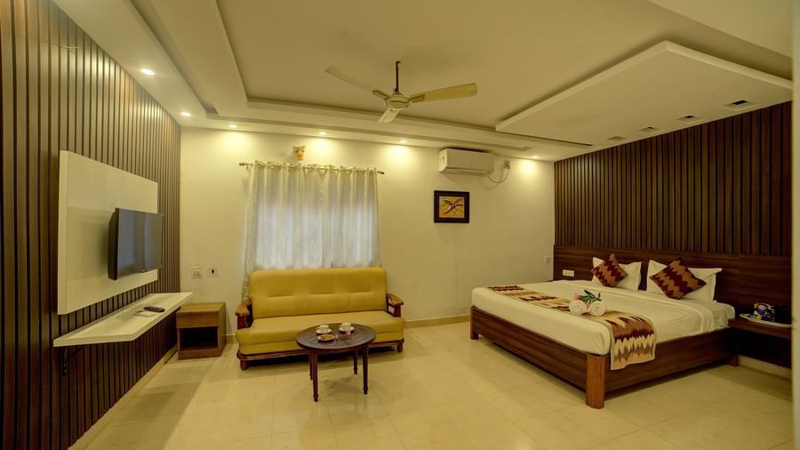 Well-lit modern room featuring a bed, sofa, and wall-mounted TV at Kailash Conventions ECR.