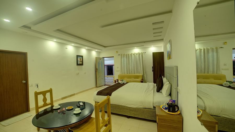 Bedroom with seating area and warm lighting at Kailash Conventions ECR.