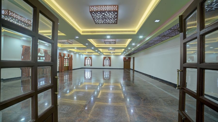 Glass-panelled hallway with symmetrical lighting and grand entryway at Kailash Conventions ECR.