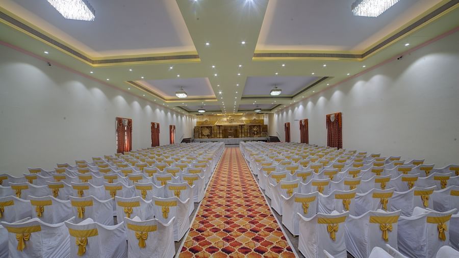 Indoor banquet hall with rows of white chairs and a central aisle at Kailash Conventions ECR.
