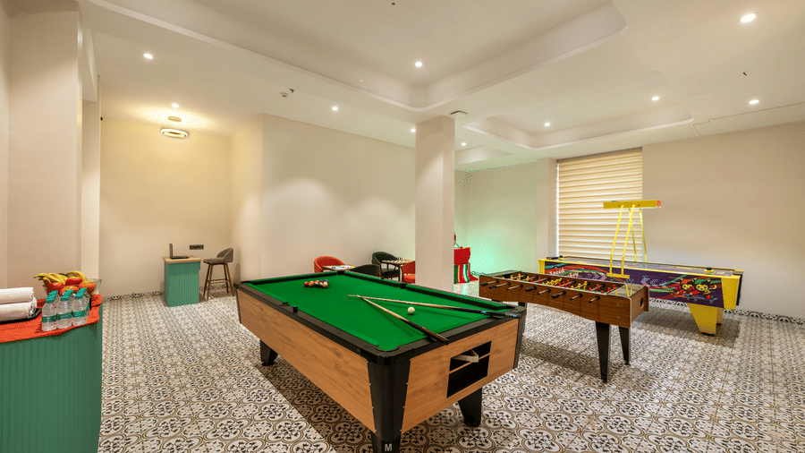 Games Room with a pool table and foosball table set on a patterned floor at Lords Inn Somnath, offering fun for guests of all ages.