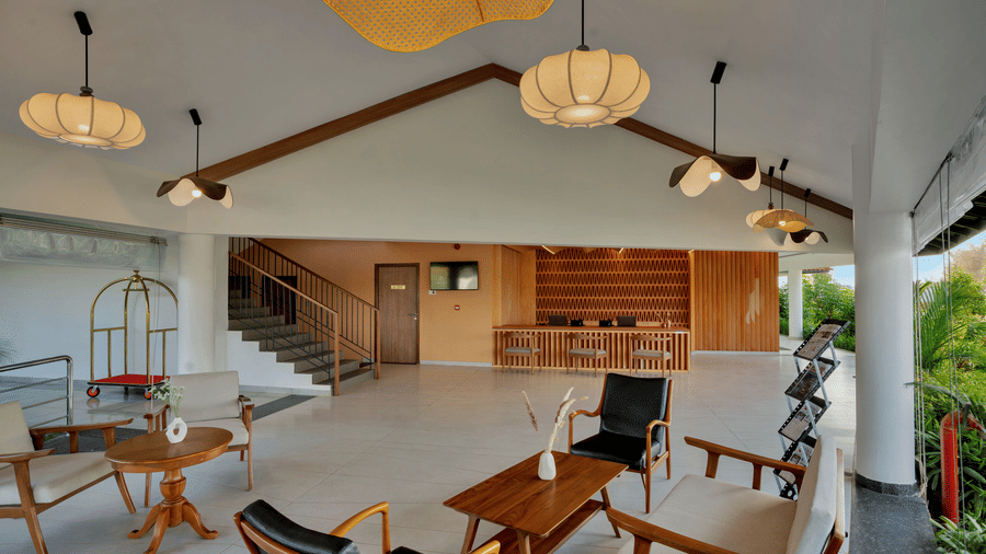 Lobby area at Mango Hill, Velankanni seating area with chairs, tables, lights, stairs, and a reception desk at one corner.