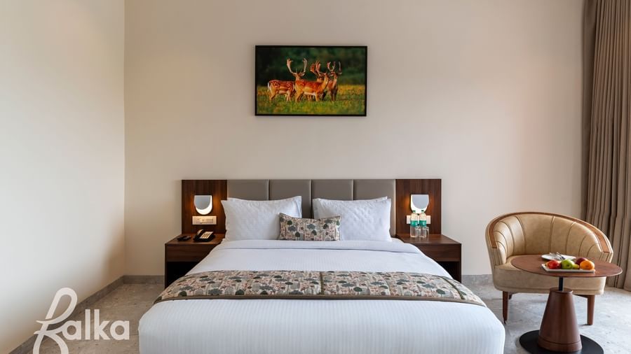 A bright bedroom at Osian Valley Resort & Spa with a double bed, bedside tables, and a painting of deer hanging above the headboard.
