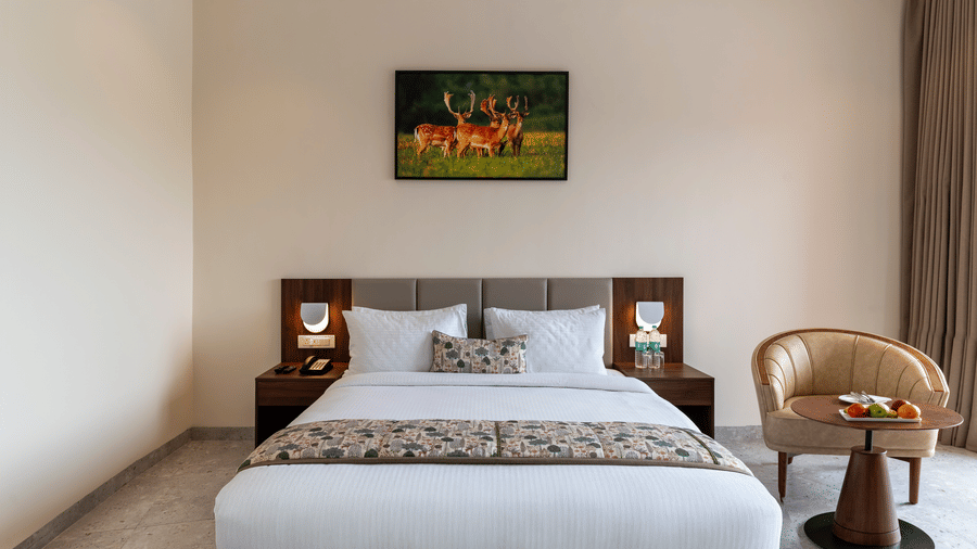 A neatly designed bedroom at Osian Valley Resort & Spa, Kumbhalgarh, featuring a comfortable double bed, soft lighting, wooden furniture, and a warm, peaceful ambience perfect for rest.