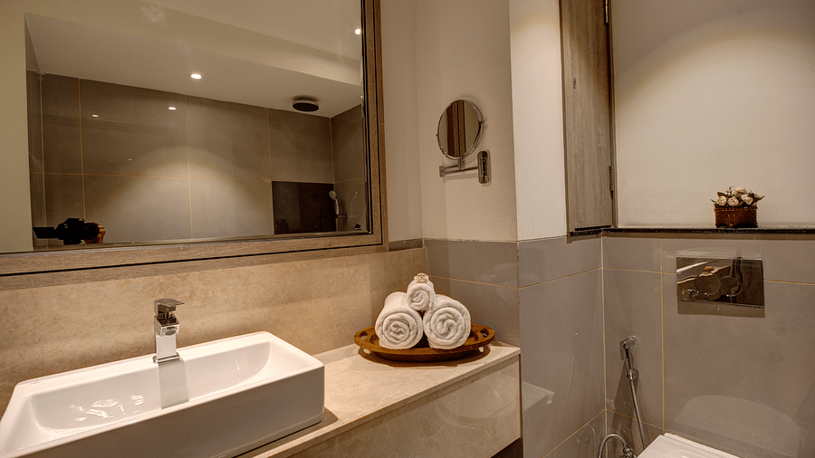 Overview of the bathroom with the sink and wash towels kept on the counter inside Premium Suite - Rhythm Gurugram