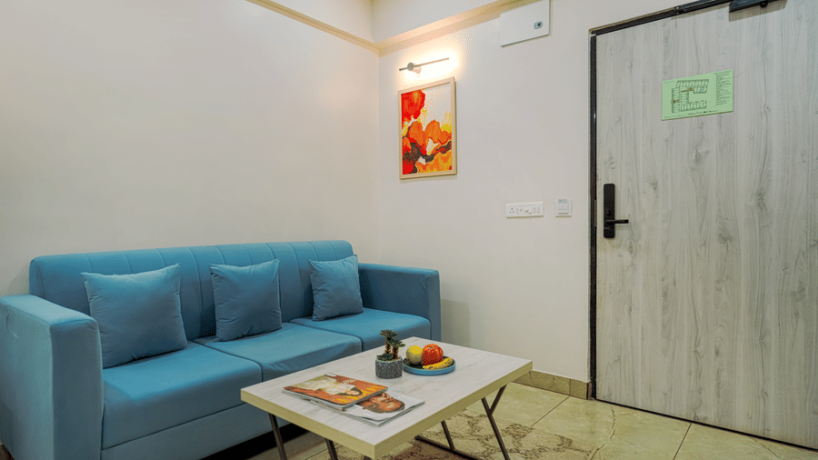 A hotel room at Urban Suites by BluSalzz, Jaipur, with a sofa, a coffee table, and a door leading to another area.