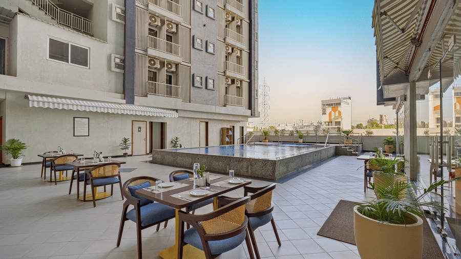 An outdoor dining area with tables and chairs next to a small pool  at Urban Suites by BluSalzz, Jaipur.