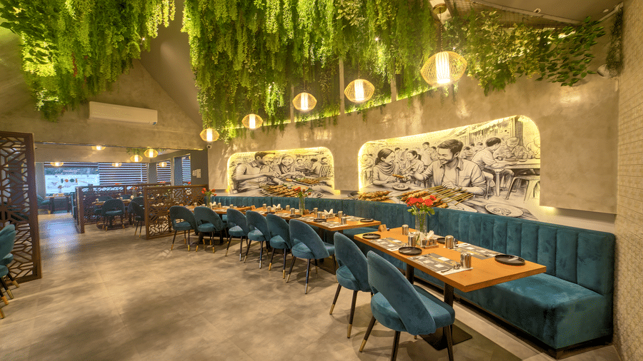Long dining table under a lush green ceiling canopy at Ilara Hotels & Spa, OMR, Chennai
