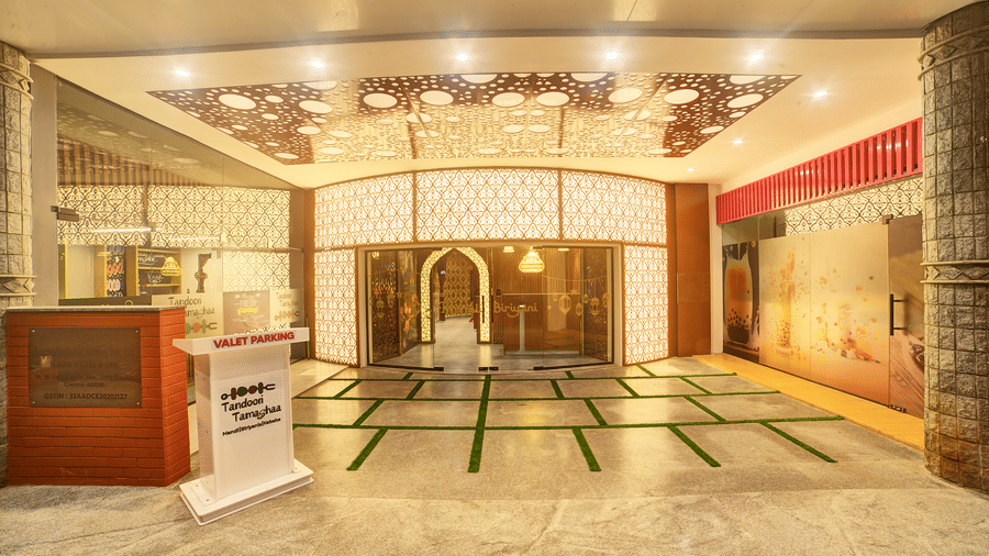 The entrance of the hotel with a grand traditional decor, wooden counter, and decorative flooring at Ilara Hotels & Spa, OMR, Chennai.