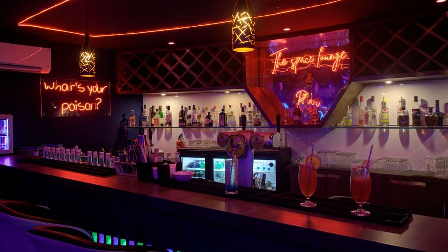 Stylish bar counter with colourful lighting and illuminated drink display at Ilara Hotels & Spa, OMR, Chennai