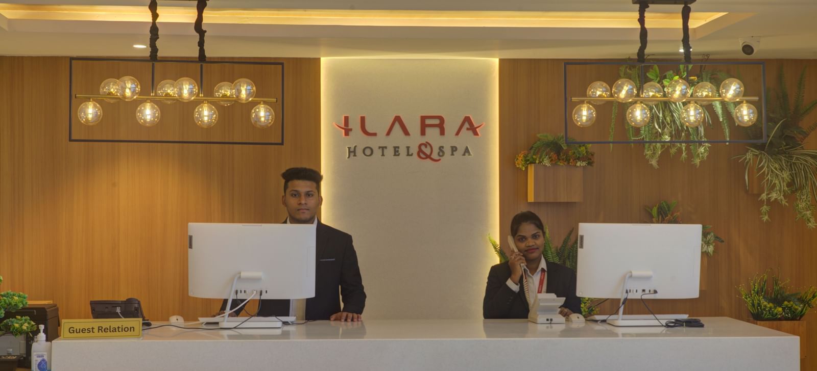 Close up shot of the reception desk at Ilara Hotels & Spa, Tada with two staff members dressed in business formals standing behind the desk.