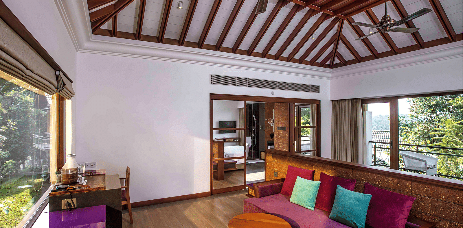 an image of a hotel room in Wayanad with a couch turned towards the beautiful view outside the room - GReaT trails Wayanad by GRT Hotels