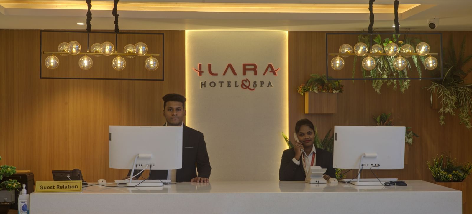 Close up shot of the reception desk at Ilara Hotels & Spa, Tada with two staff members standing behind the desk.