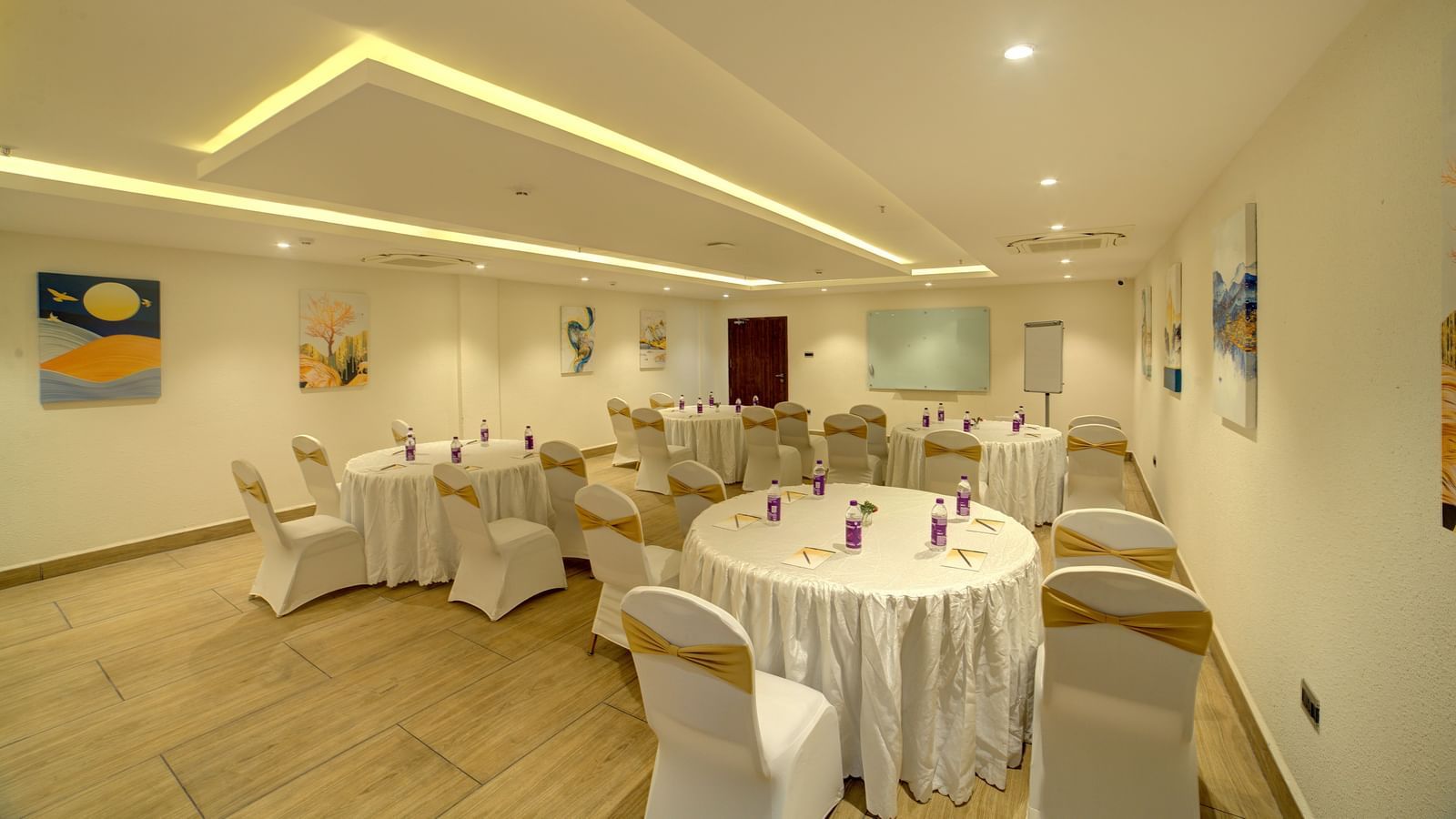 Corner view shot of a banquet hall with chairs and tables arranged for a fall event facing towards the projector at Ilara Hotels & Spa, Tada.
