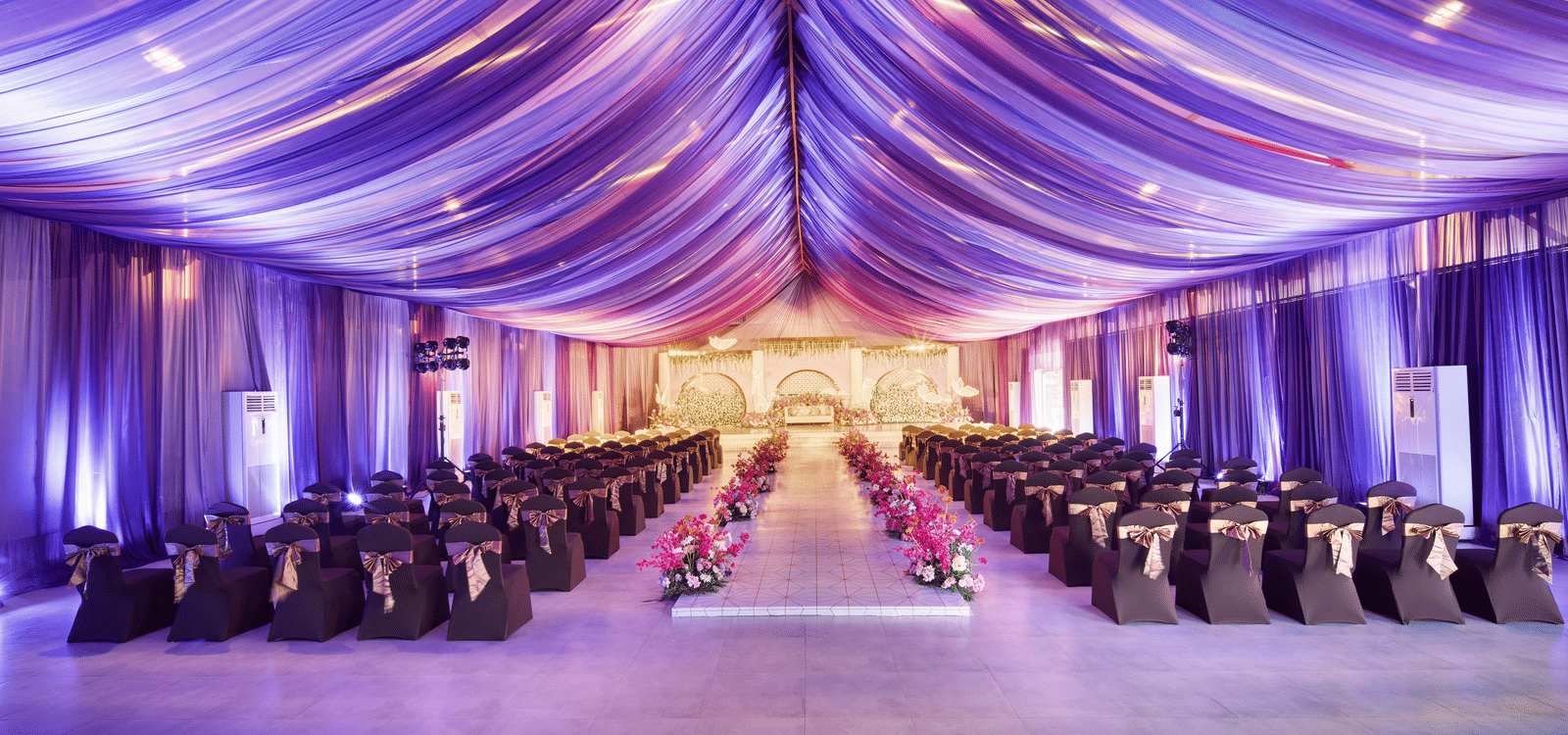Indoor wedding hall with flowing purple draped ceiling and neatly arranged theatre style seating - Grande Bay Resort & Spa, Mamallapuram