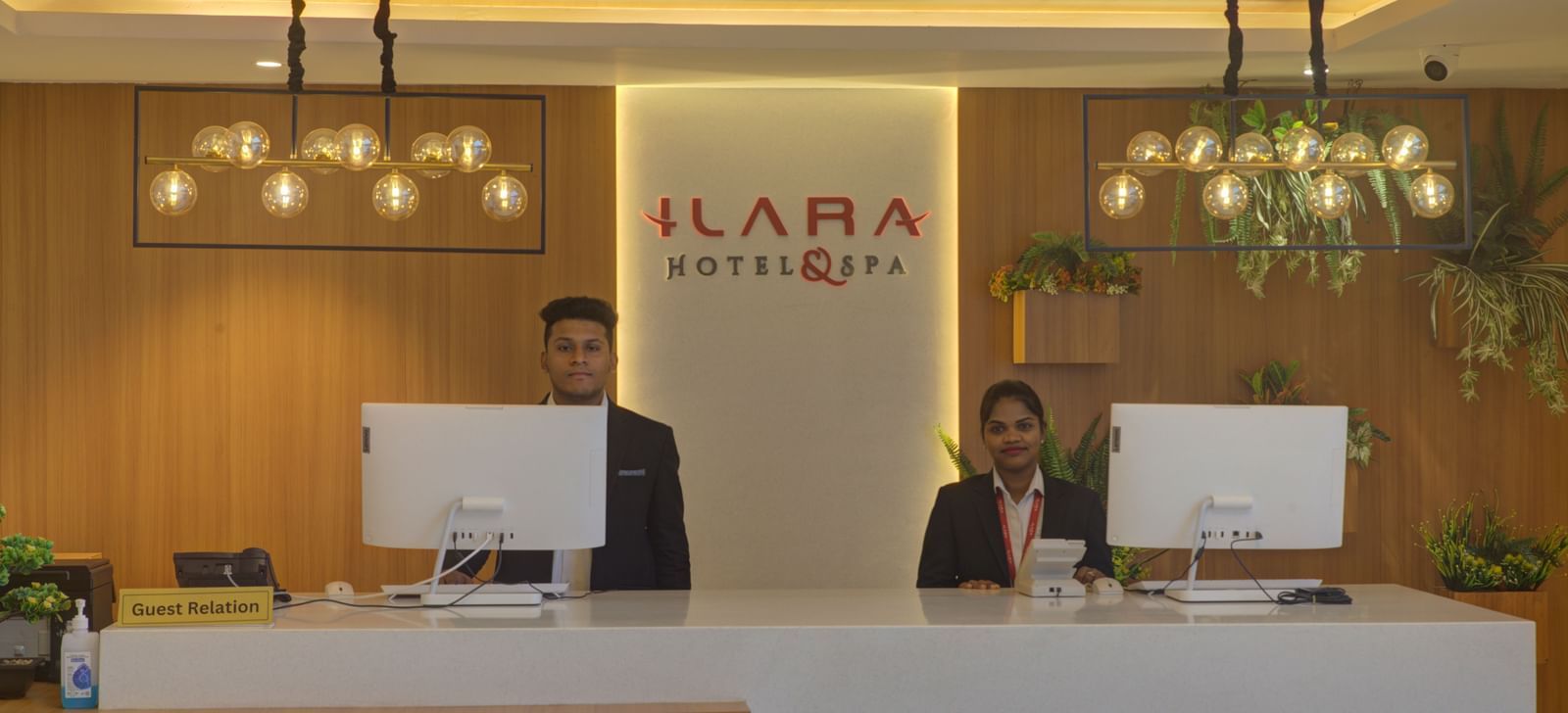 The reception desk at Ilara Hotels & Spa, Tada with two staff members dressed in business formals standing behind the desk.