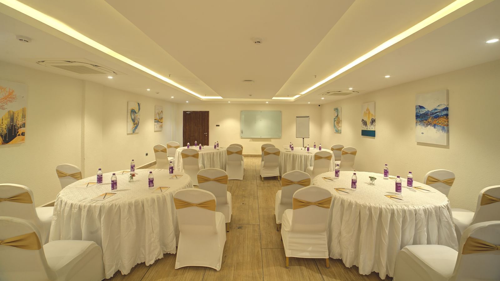 Full view shot of the banquet hall with some walking space in the middle leading towards the projector screen at the far end of the hall at Ilara Hotels & Spa, Tada.