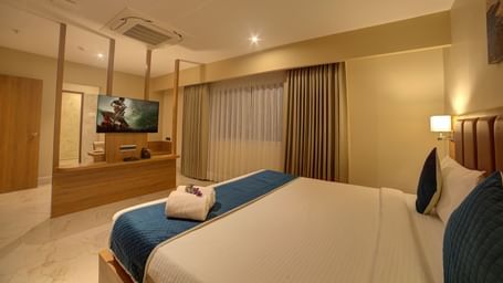 A wide angle shot of the bedroom at Ilara Hotels & Spa, Tada at the Executive Suite with a plush double bed and a flat screen television in front of it.