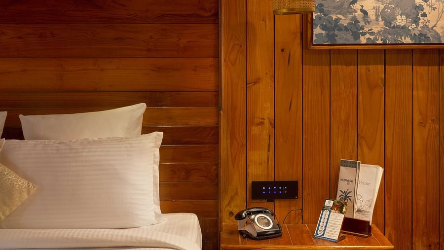 Image of pillows arranged on a bed next to which a nightstand is placed in  Coral Turquoise at Coral Reef Resort and Spa in Havelock
