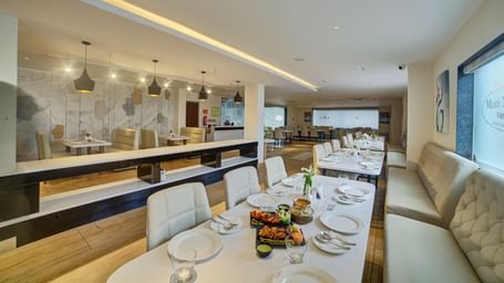 The interiors of a brightly lit dining area with beautifully served dishes on the table at Ilara Hotels & Spa, Tada.
