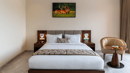 A neatly designed bedroom at Osian Valley Resort & Spa, Kumbhalgarh, featuring a comfortable double bed, soft lighting, wooden furniture, and a warm, peaceful ambience perfect for rest.