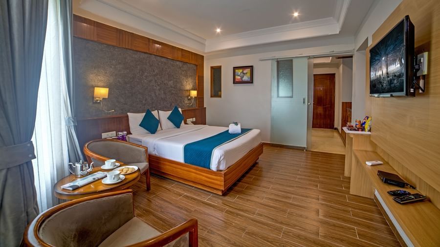 Well-appointed guest room with wooden flooring, modern furnishings, and a cosy seating area at Ilara Hotels & Spa, OMR, Chennai