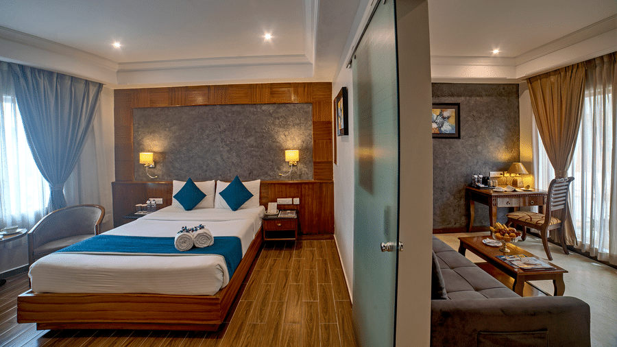 Elegant bedroom with a glass partition separating the living space at Ilara Hotels & Spa, OMR, Chennai