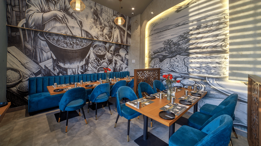 Cosy dining table setup with mural background and velvet chairs at Ilara Hotels & Spa, OMR, Chennai