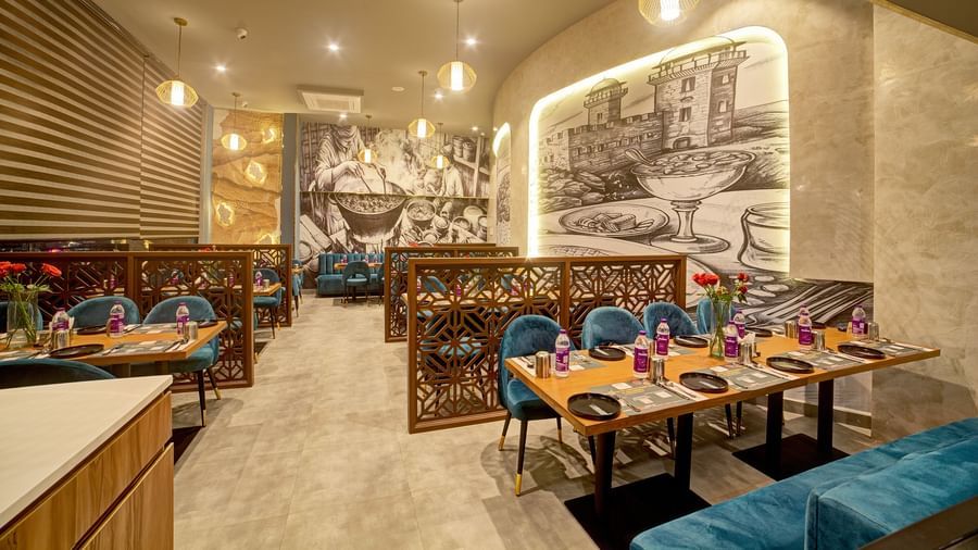 Restaurant booth seating with classic artwork on the walls at Ilara Hotels & Spa, OMR, Chennai
