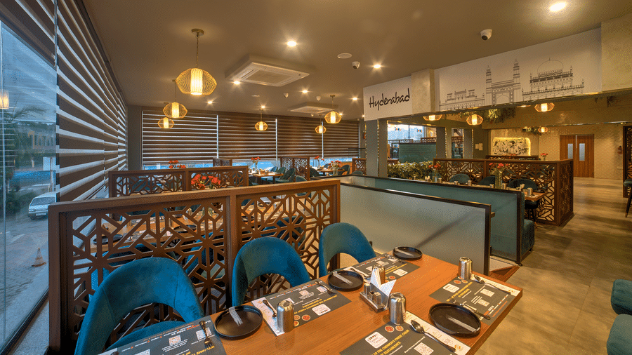 Wide-angle view of the restaurant with blue chairs and warm lighting at Ilara Hotels & Spa, OMR, Chennai