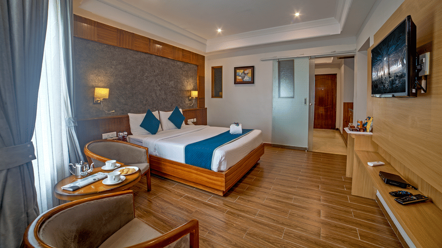 Well-appointed guest room with wooden flooring, modern furnishings, and a cosy seating area at Ilara Hotels & Spa, OMR, Chennai