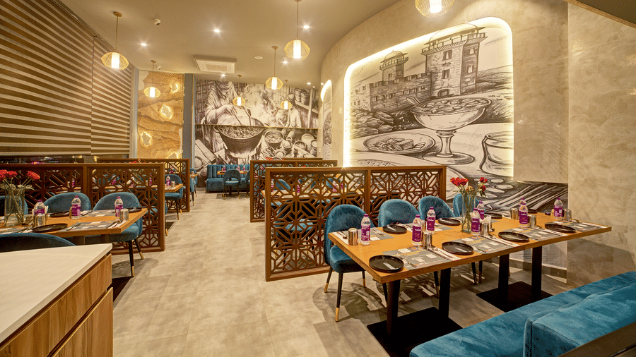 Restaurant booth seating with classic artwork on the walls at Ilara Hotels & Spa, OMR, Chennai