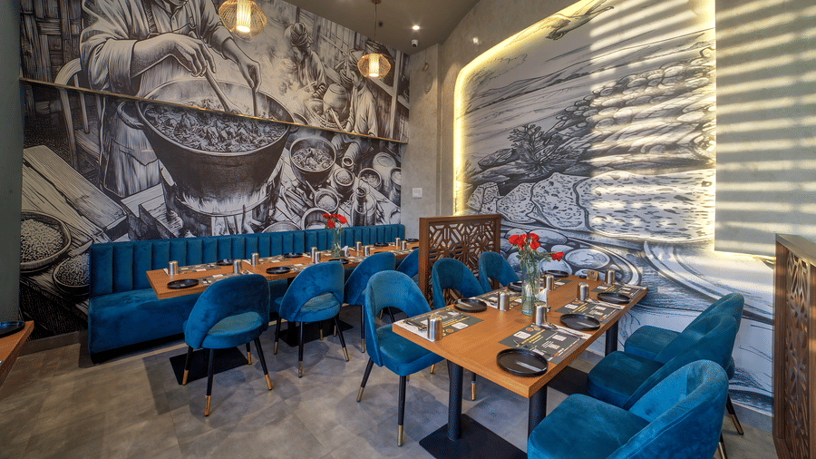 Cosy dining table setup with mural background and velvet chairs at Ilara Hotels & Spa, OMR, Chennai
