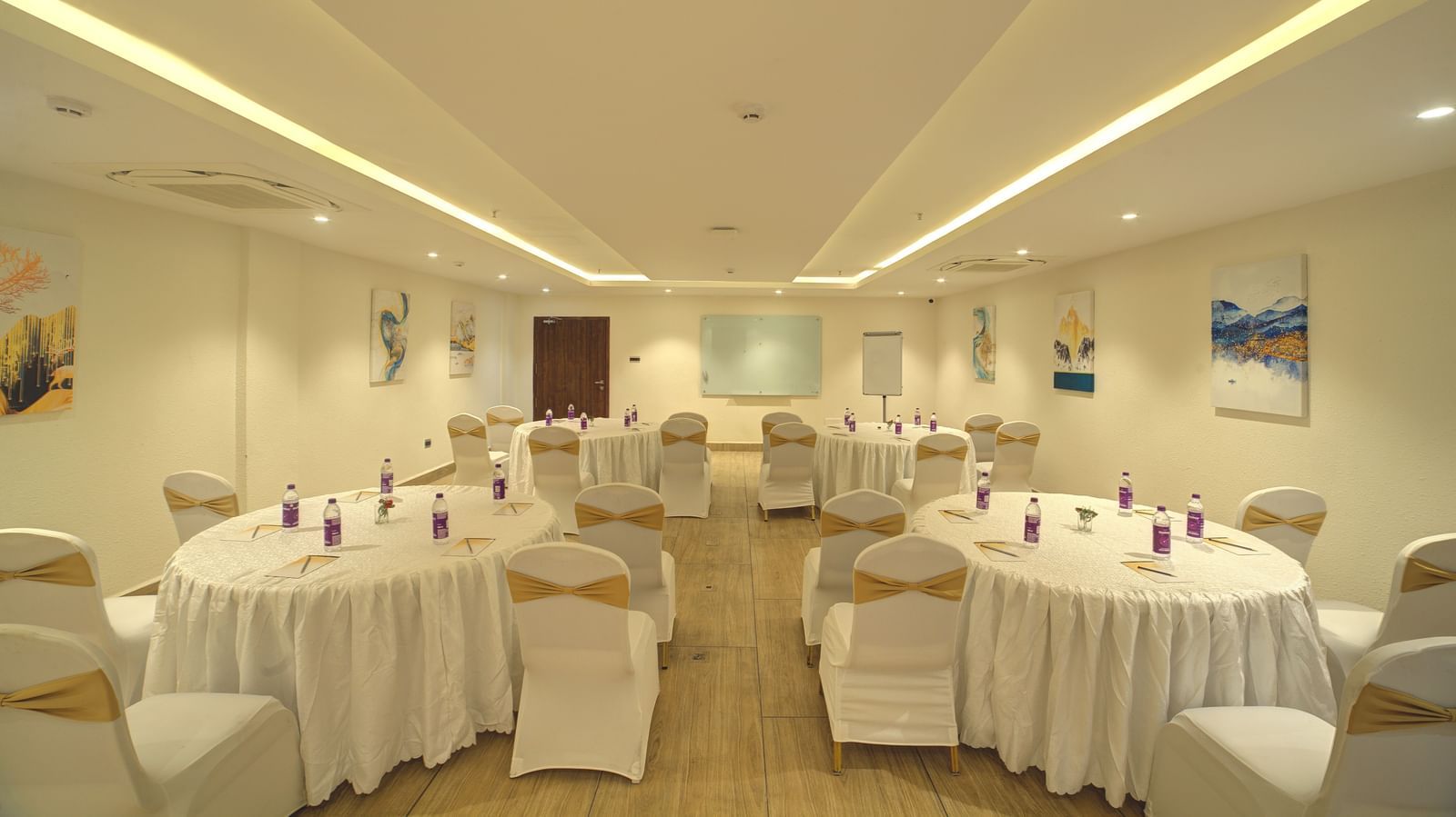 Full view shot of the banquet hall with some walking space in the middle leading towards the projector screen at the far end of the hall at Ilara Hotels & Spa, Tada.