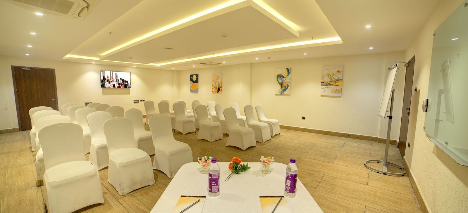 Corner view shot of the banquet hall featuring a table in the foreground with some stationary and packed water bottles at Ilara Hotels & Spa, Tada.